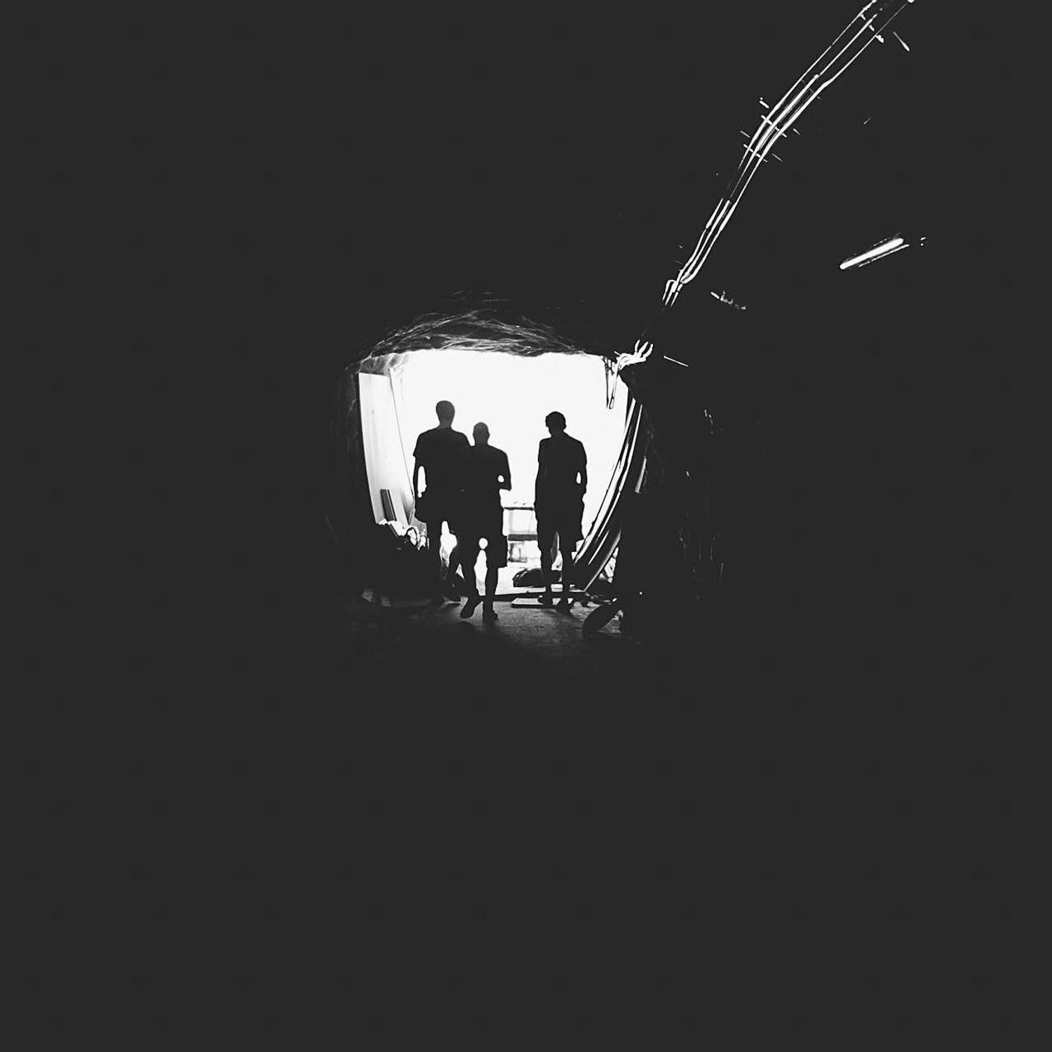Two figures silhouetted in a tunnel mouth