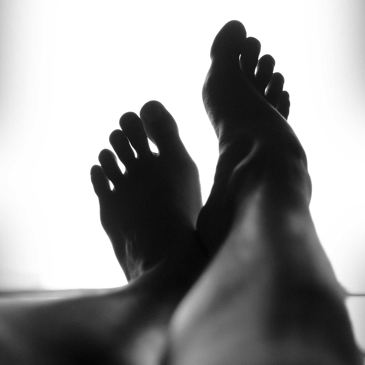 Bare feet crossed in low light, detail frame