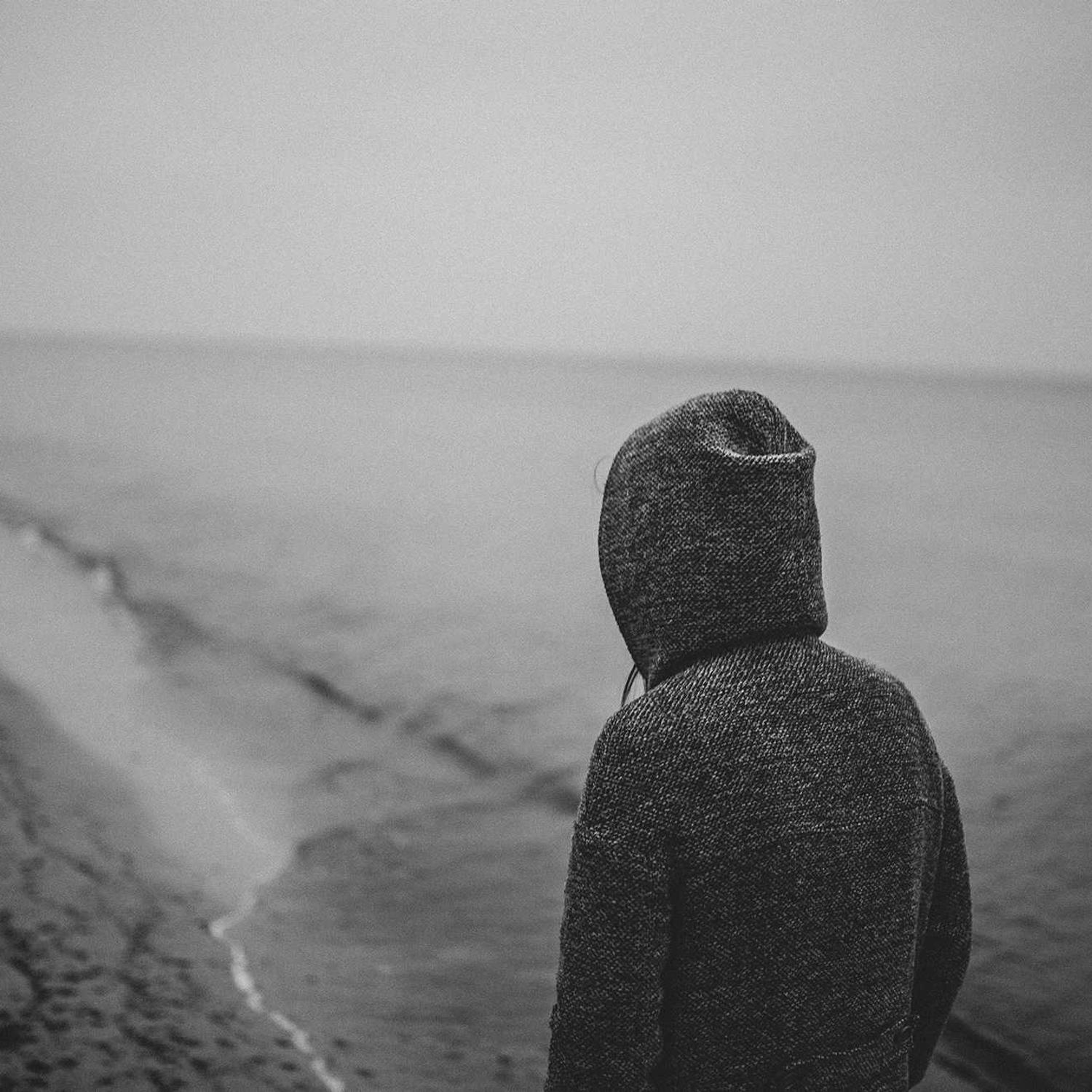 Hooded figure facing the sea