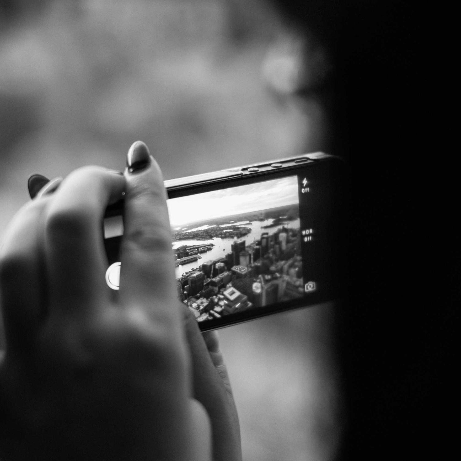 Hand raising a phone to shoot a moving street