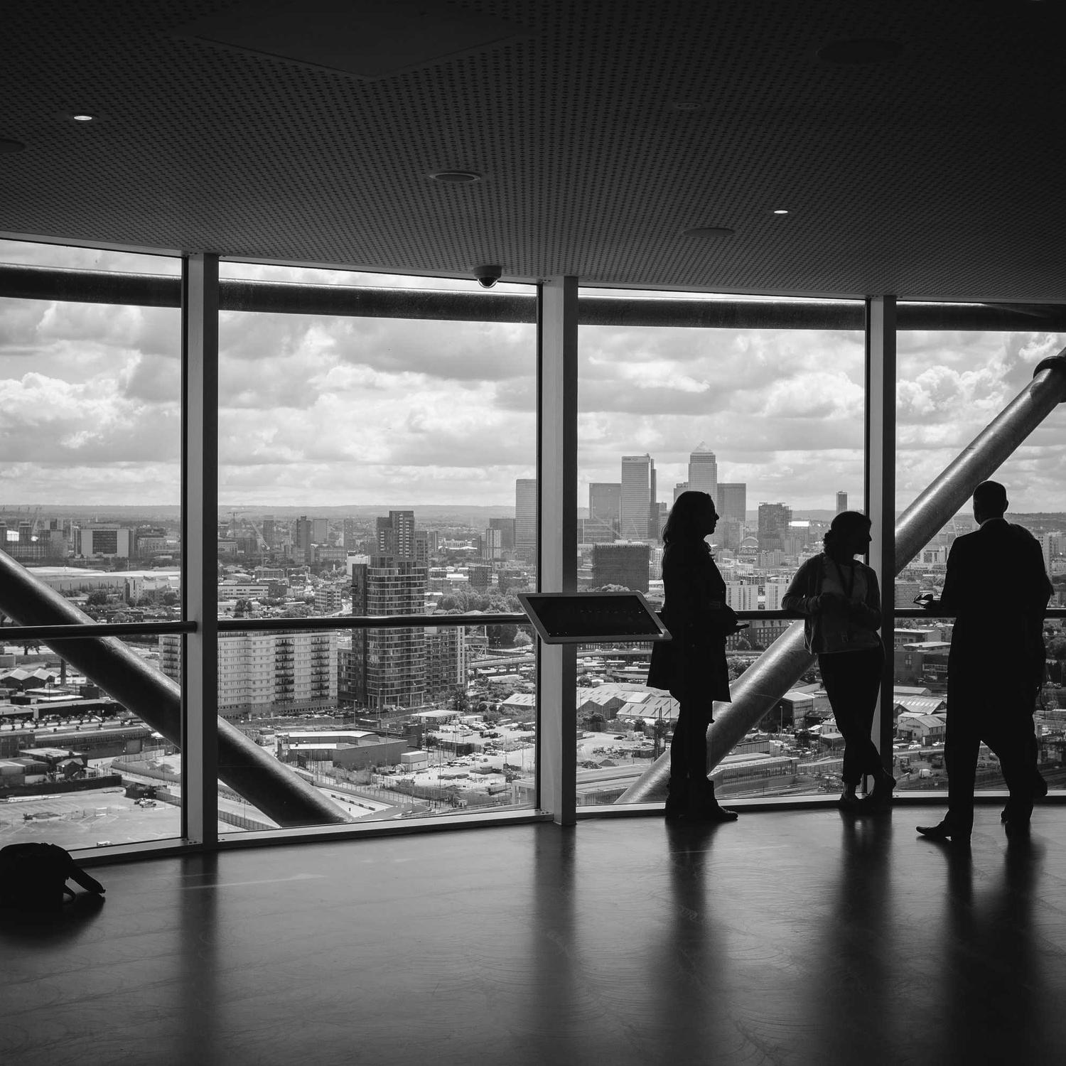 Two figures at a window above the city, interior shadow