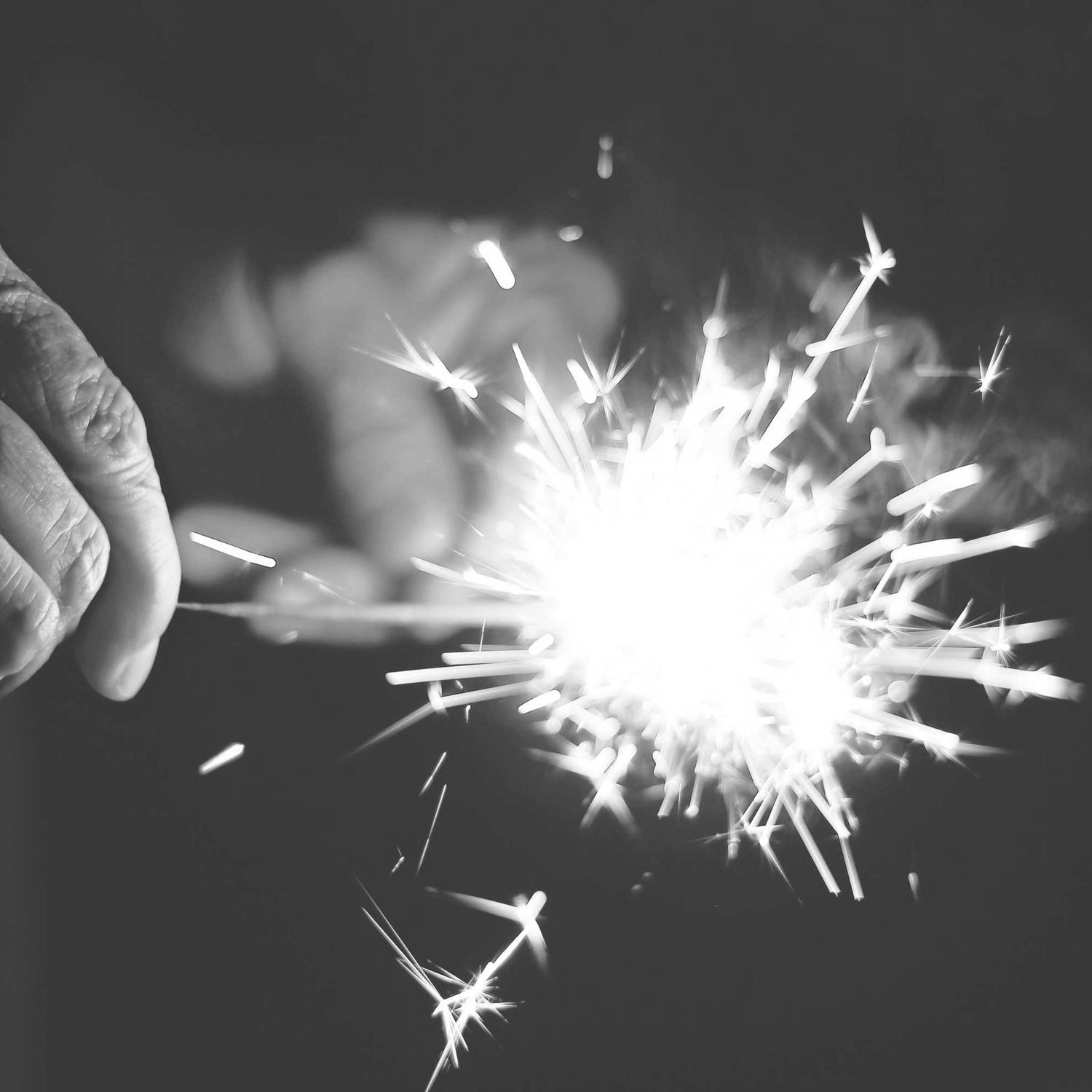 Sparkler burst in the dark, hands just visible