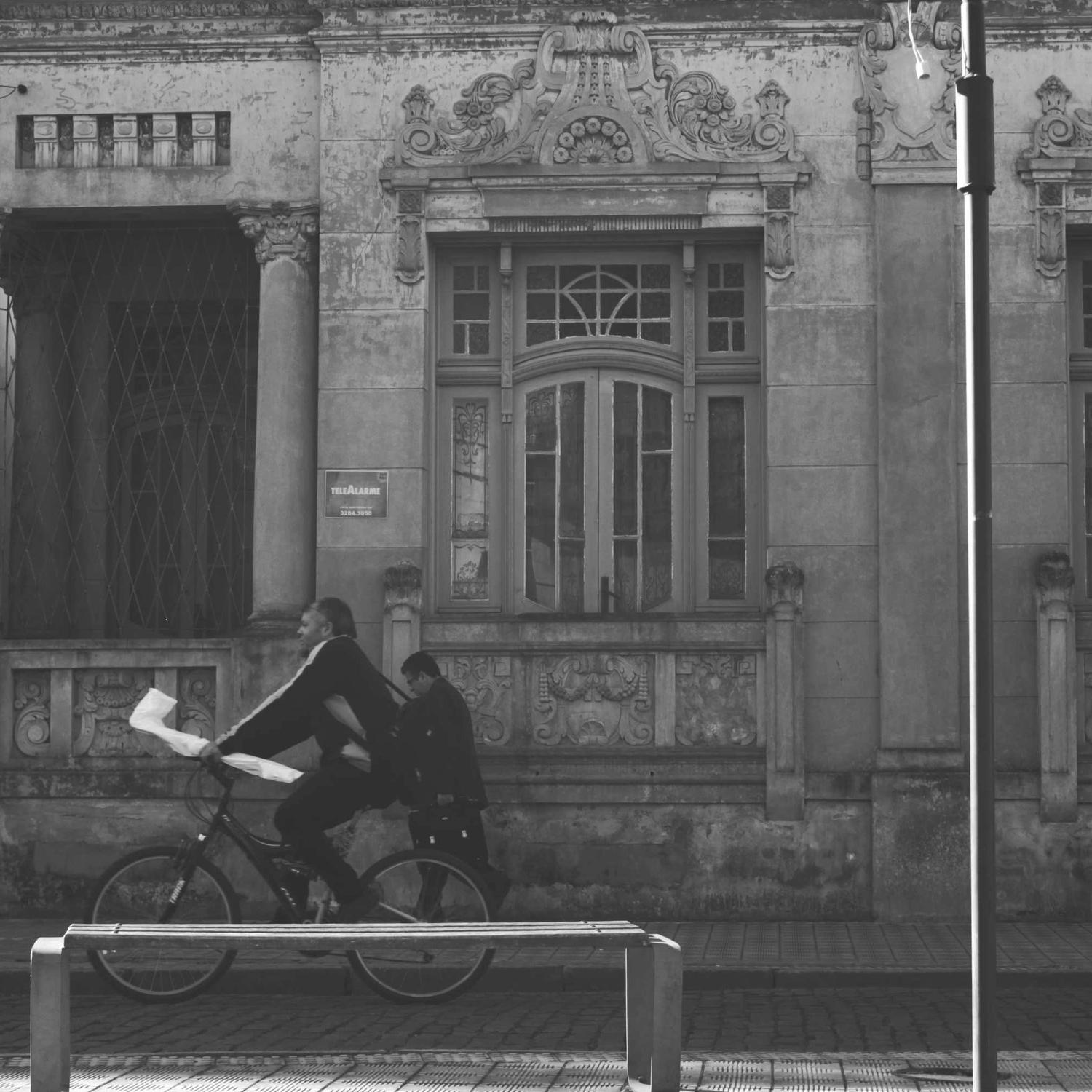 Full-length by a carved façade, bicycle passing