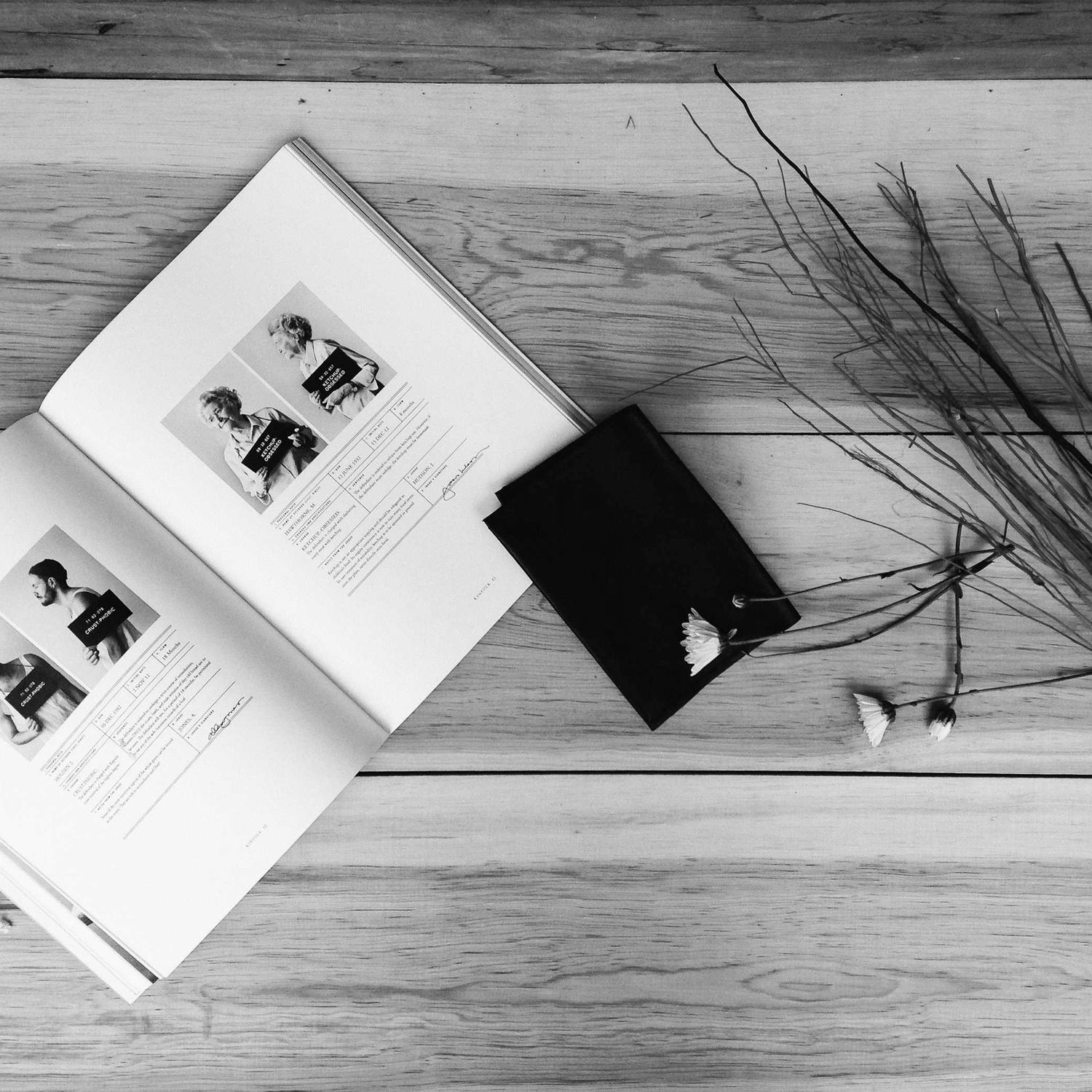 Open book and dark accessories on a table, styled flat