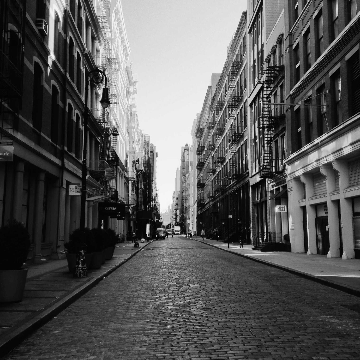 Narrow street canyon between old buildings, monochrome