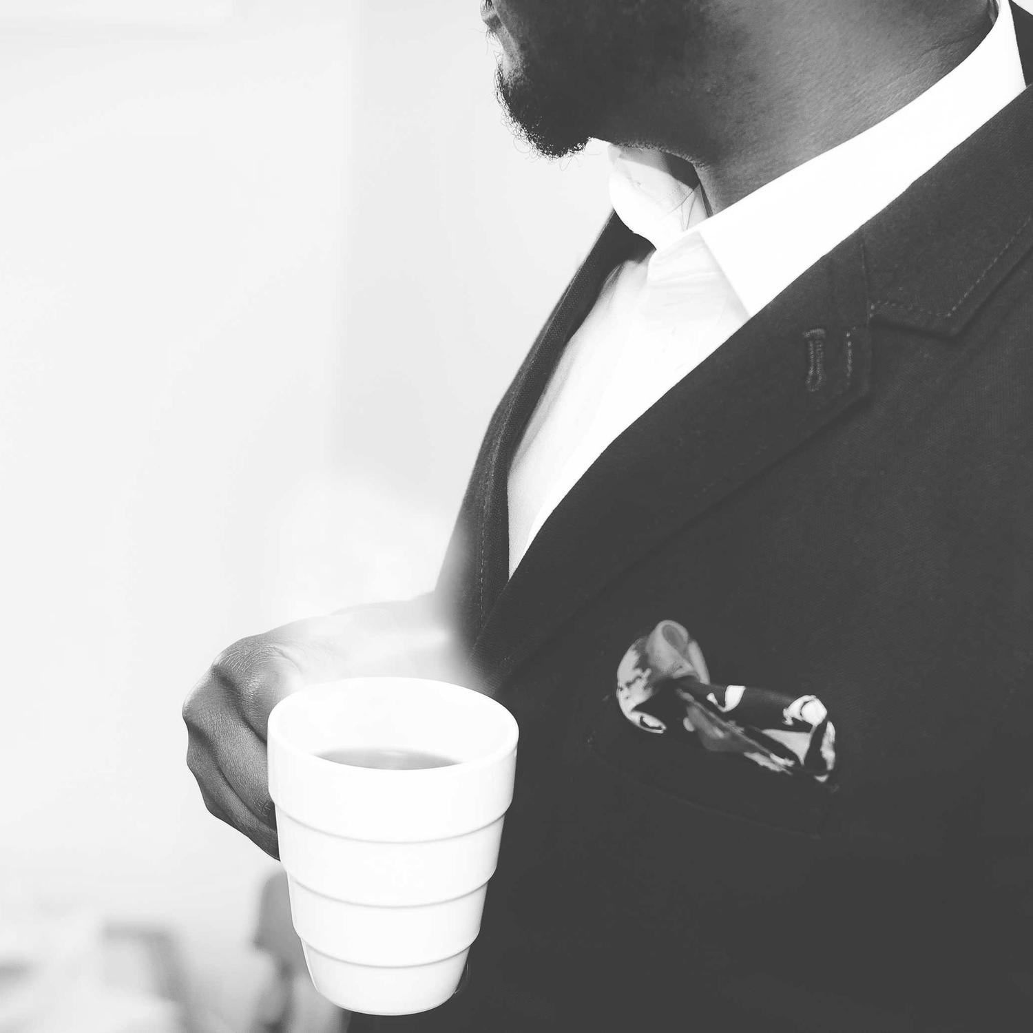 Detail of a tailored suit and a coffee cup, monochrome
