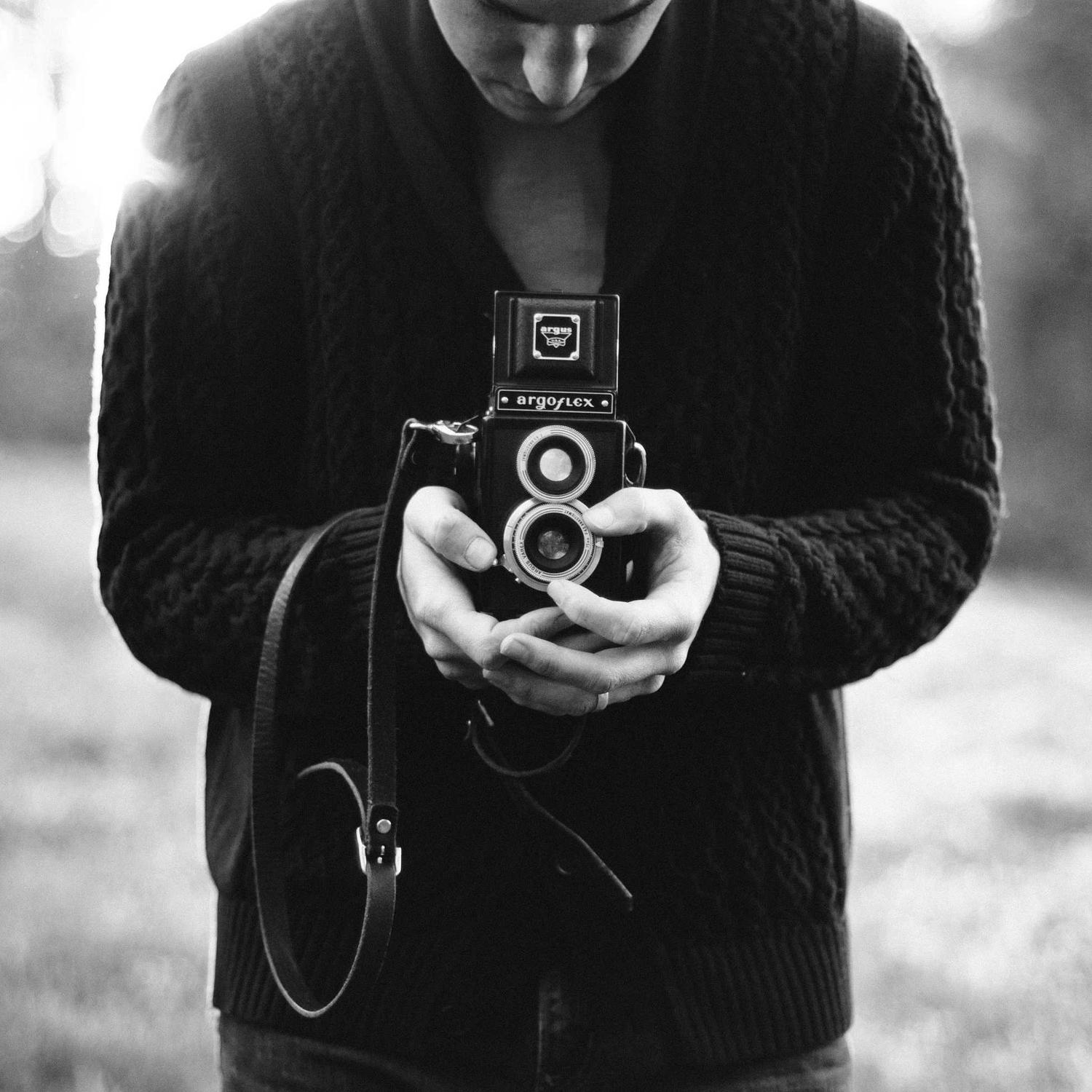 Hands holding a medium-format camera, monochrome